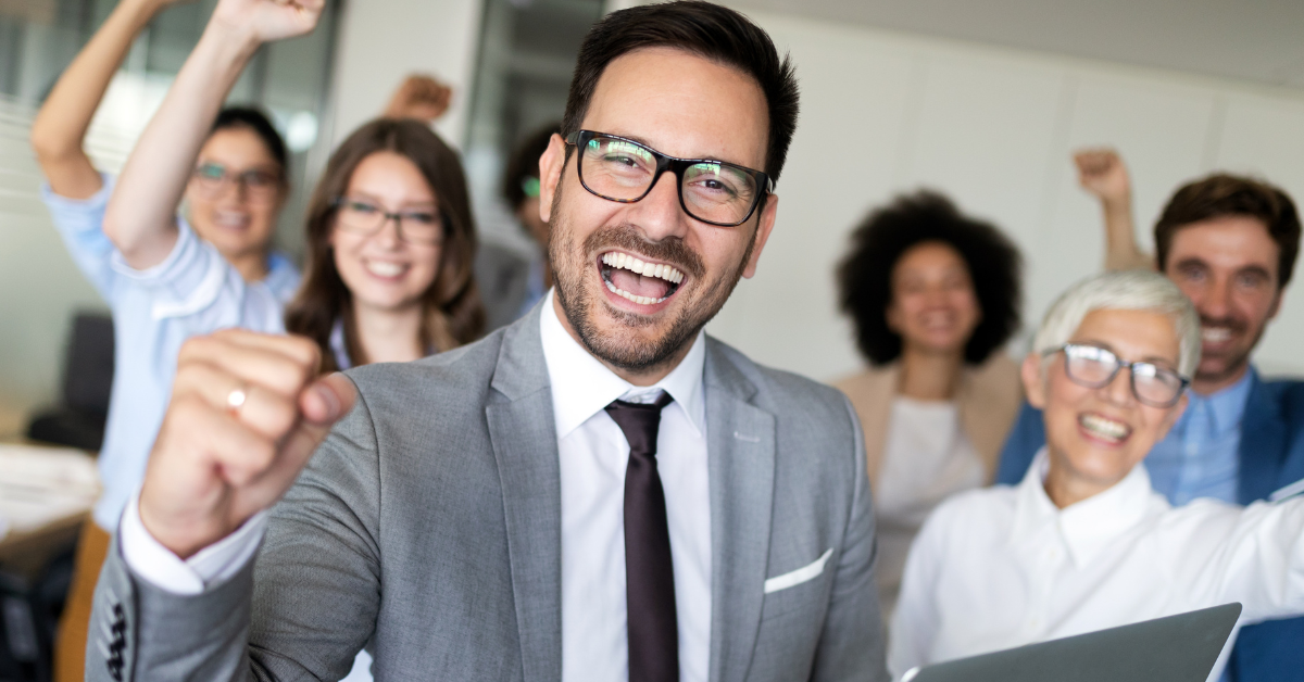 A cheerful and diverse business team celebrating a win, symbolizing success through strategic IT outsourcing.
