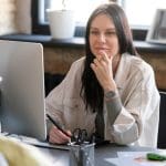 A developer smiling while holding a laptop with a JavaScript