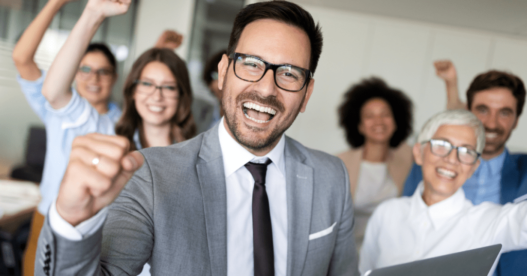 A cheerful and diverse business team celebrating a win, symbolizing success through strategic IT outsourcing.