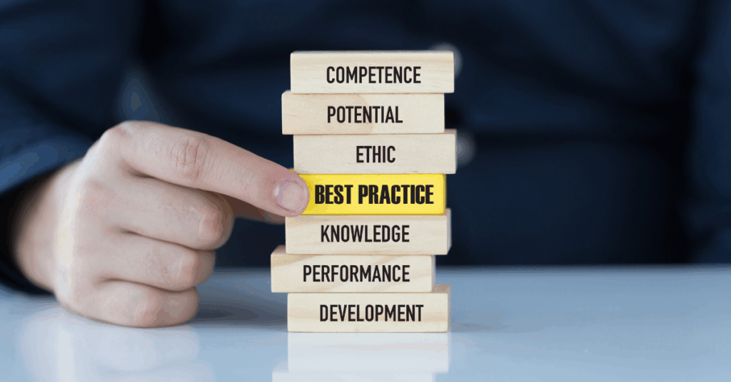 A hand pulling a wooden block labeled “Best Practice” from a stack of blocks featuring values like competence, knowledge, and development.