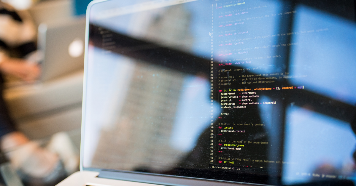 Laptop screen showing highlighted code, with reflections in the background, indicating a focused software development environment.