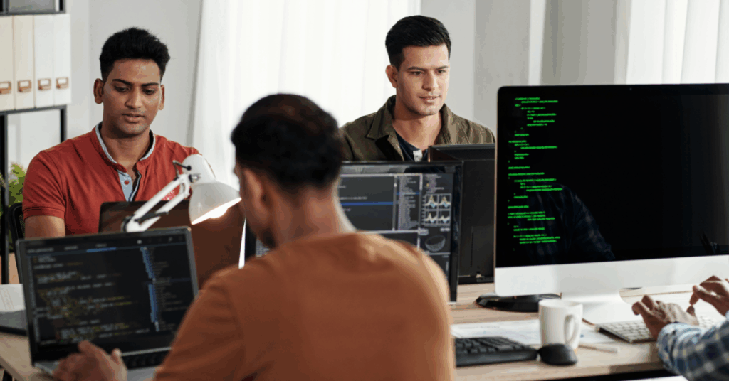 Group of software developers working at their computers in a modern office, collaborating on Golang-based projects.
