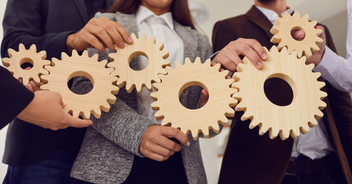 Teamwork concept with professionals connecting large wooden gears in business collaboration.