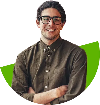parallelstaff- A smiling person with dark hair and glasses, wearing an olive green button-up shirt, stands with arms crossed in front of a green abstract shape.
