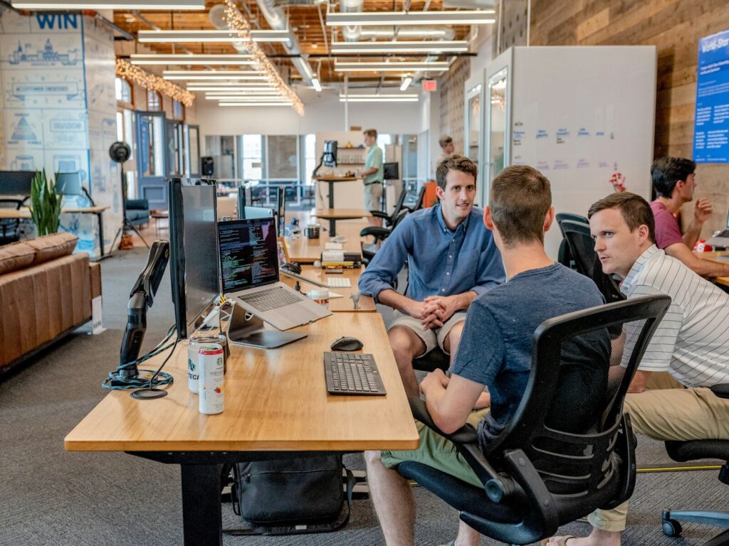 three men sittingsoftware development on nearshore on chair beside tables