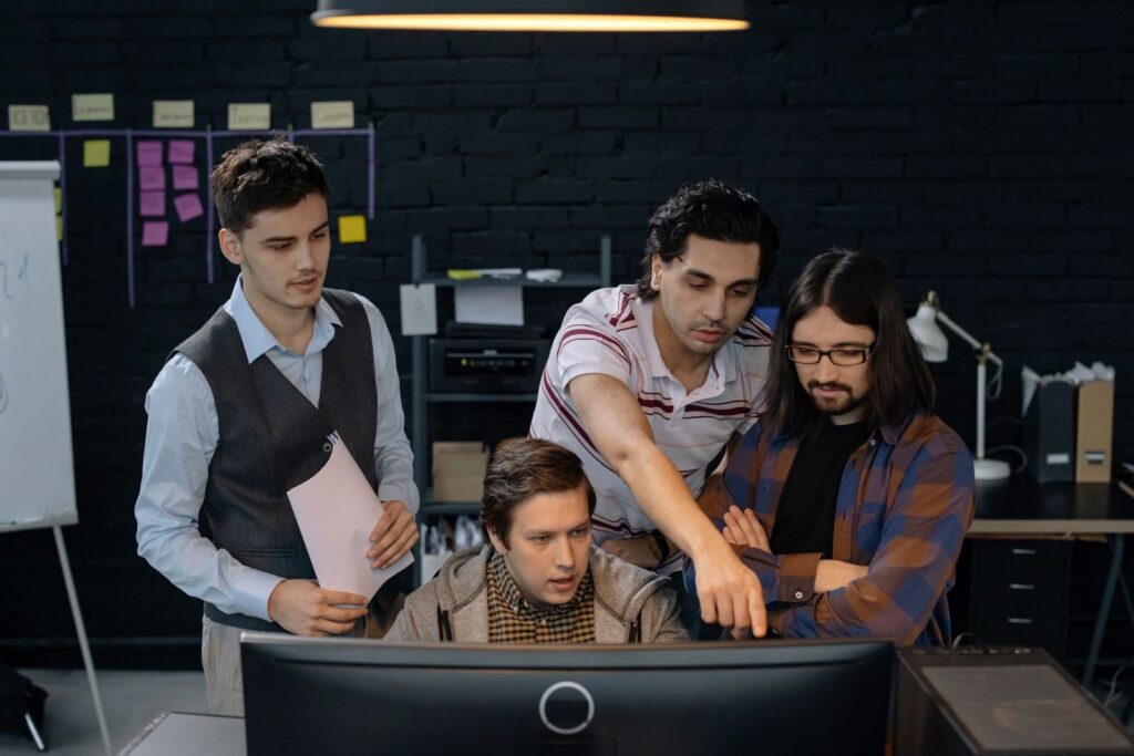 latam software engineers discussing a project at a computer in a modern office environment.