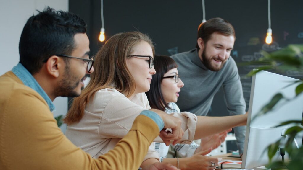 Diverse team collaborating around a computer screen